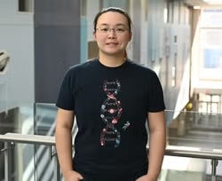 Person standing indoors wearing a black t-shirt with a colorful vertical design