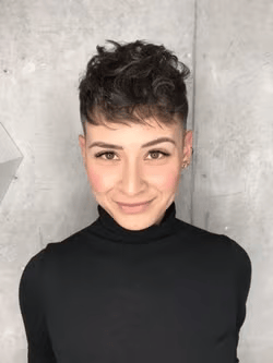 Person wearing a black turtleneck standing in front of a grey wall 