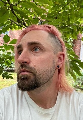 Person with pink hair looking to the left.