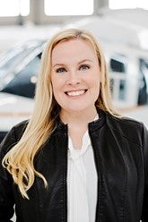 Smiling woman with blonde hair and a black jacket.