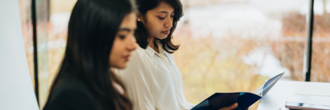 Two people are reading files sitting at a desk