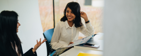 Two female students chatting and smiling while working in the Tatham Centre