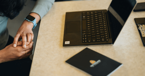 A laptop sitting on a desk next to a University of Waterloo branded booklet