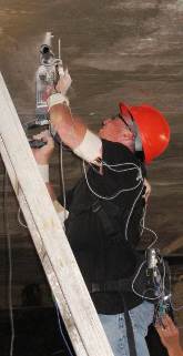 A person drilling holes in the ceiling using ladder