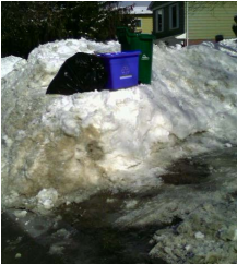 Recycling bins and garbage bags on large snow bank