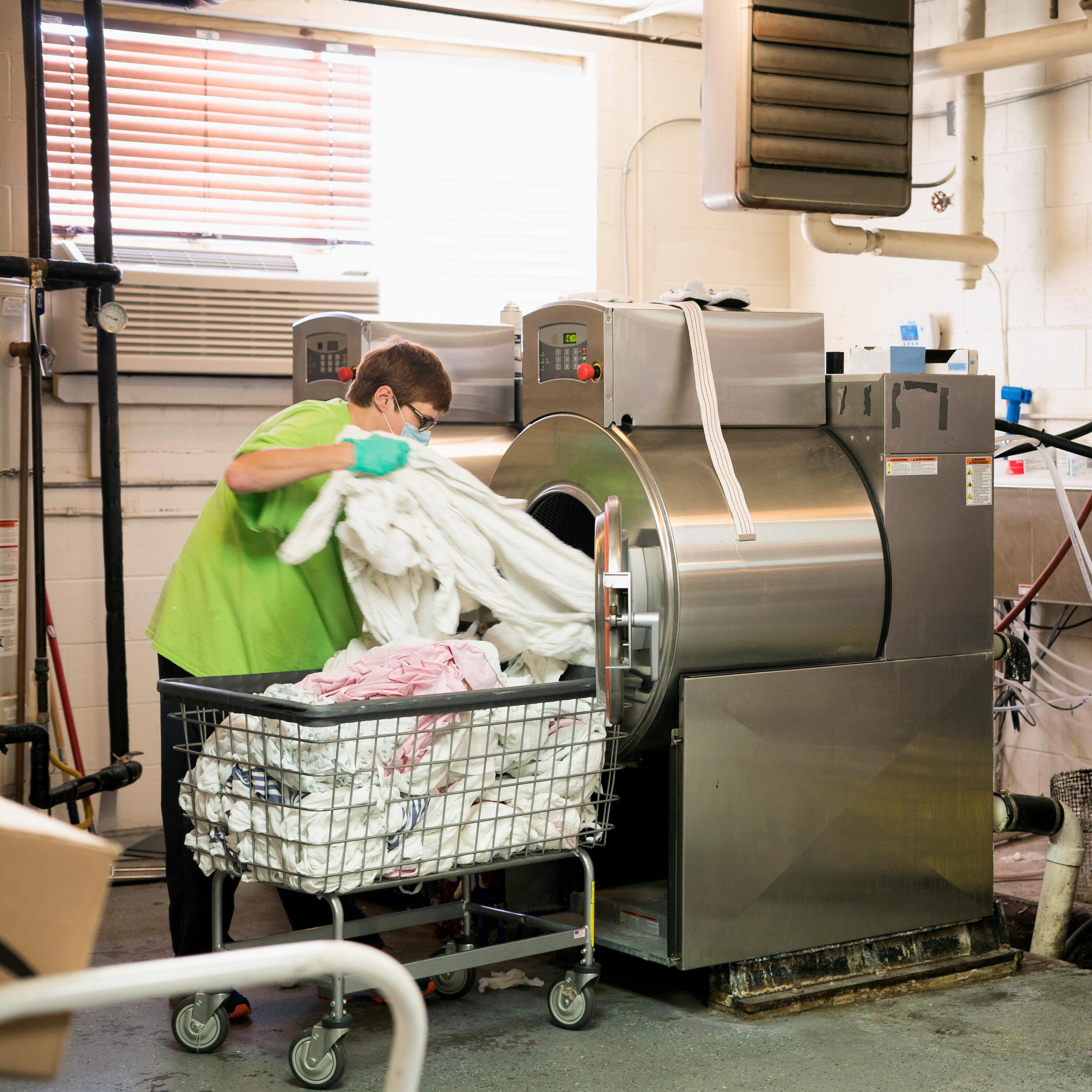 A person handling laundry in a hospital setting