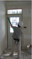 Worker finishing drywall using pneumatic drywall finishing system