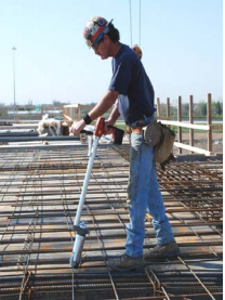 Worker using rebar-tying tool with coiled spring wire handle