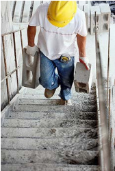 Worker manually transporting materials up stairs
