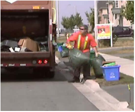 Man placing garbage bags into garbage truck