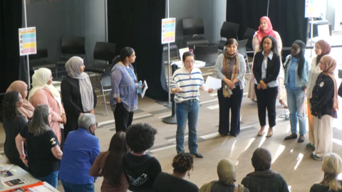 A group of women stand in a circle participating in workshop led by WPSO