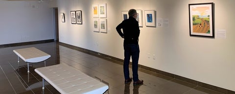 Troy Osborne stands in Grebel Gallery looking at a painting