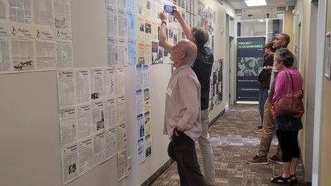 Guests attending the launch party for Ploughshares' exhibit look at a wall of 200 Ploughshares Monitors covers from the last 50 years
