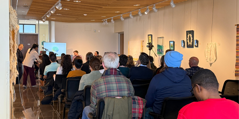 rows of people seated facing a tv screen and speakers