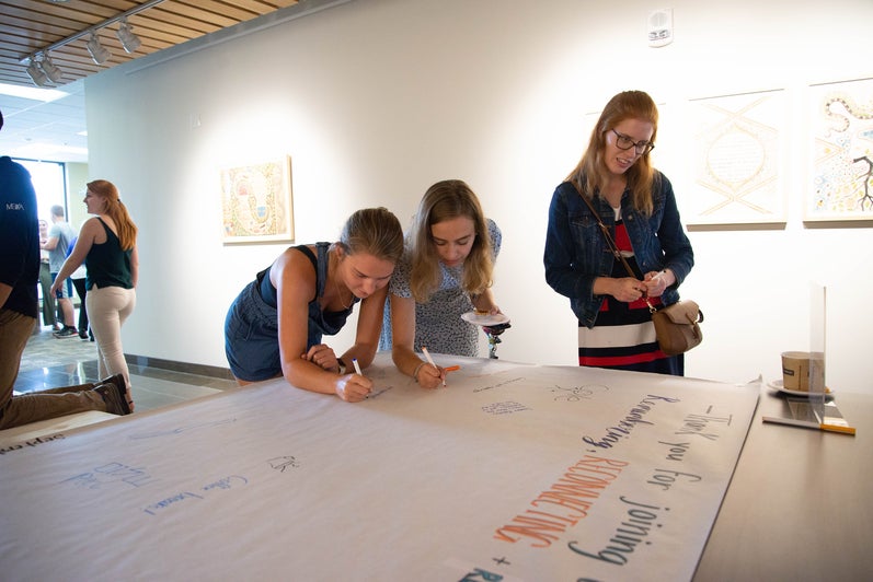 Students signing their names on a large visitor log for the Grebel Gallery