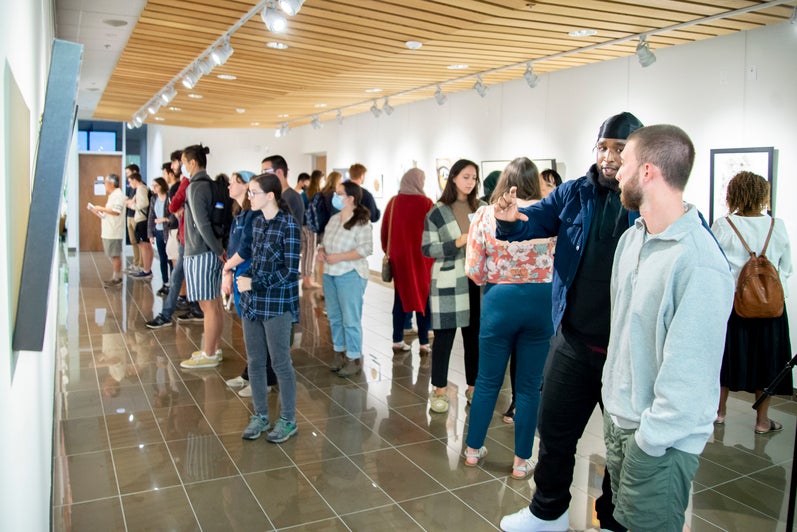A large line of students looking at a wall in the Grebel Gallery displaying paintings