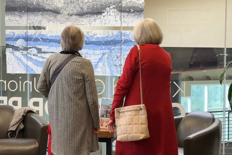 Two women looking at the wide skyline pictures on the internal glass wall