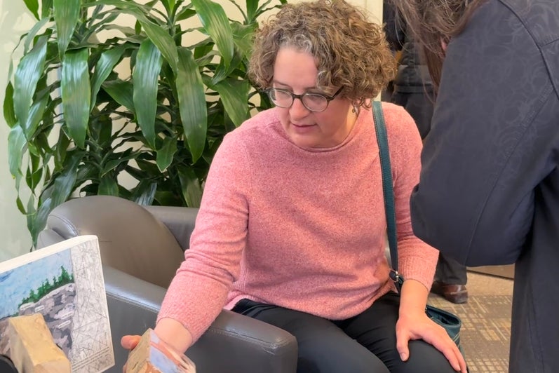 Woman feeling the weight of the art on wood that viewers were invited to touch