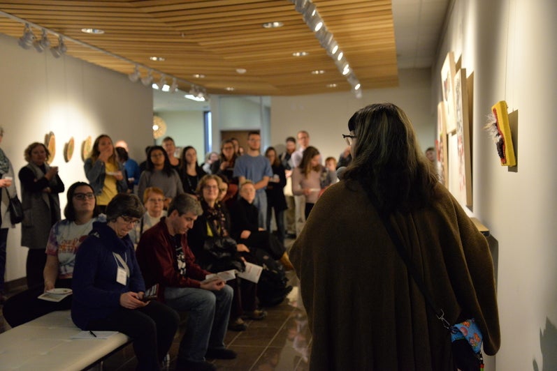 Catherine Dallaire speaking about the art pieces while guests listen attentively
