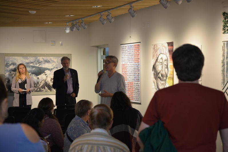 Heng-Gil Han showing speaking to guests about paintings