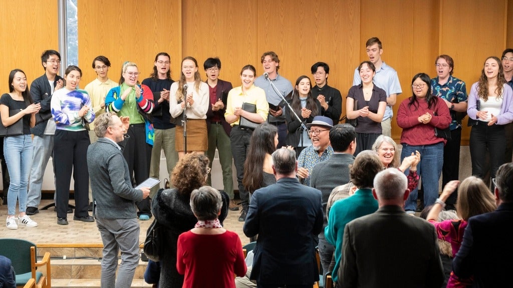 group of people surrounding a mic singing