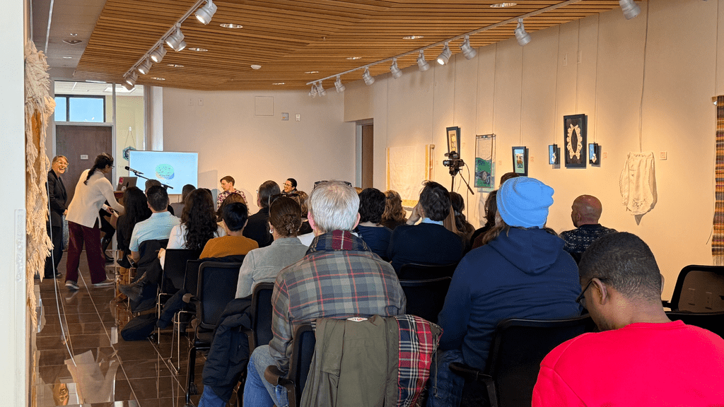 rows of people seated facing a tv screen and speakers