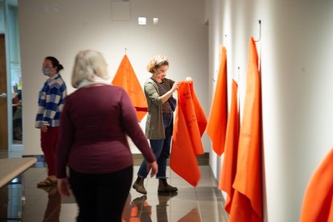 Amy Zavitz of Kindred Credit Union holds up an orange blanket at the Grebel Gallery