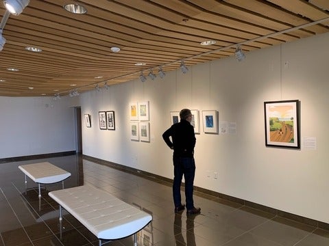 Troy Osborne stands in the Grebel Gallery looking at the art
