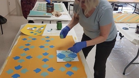 Woman printing blue tulips on a canvas floor mat