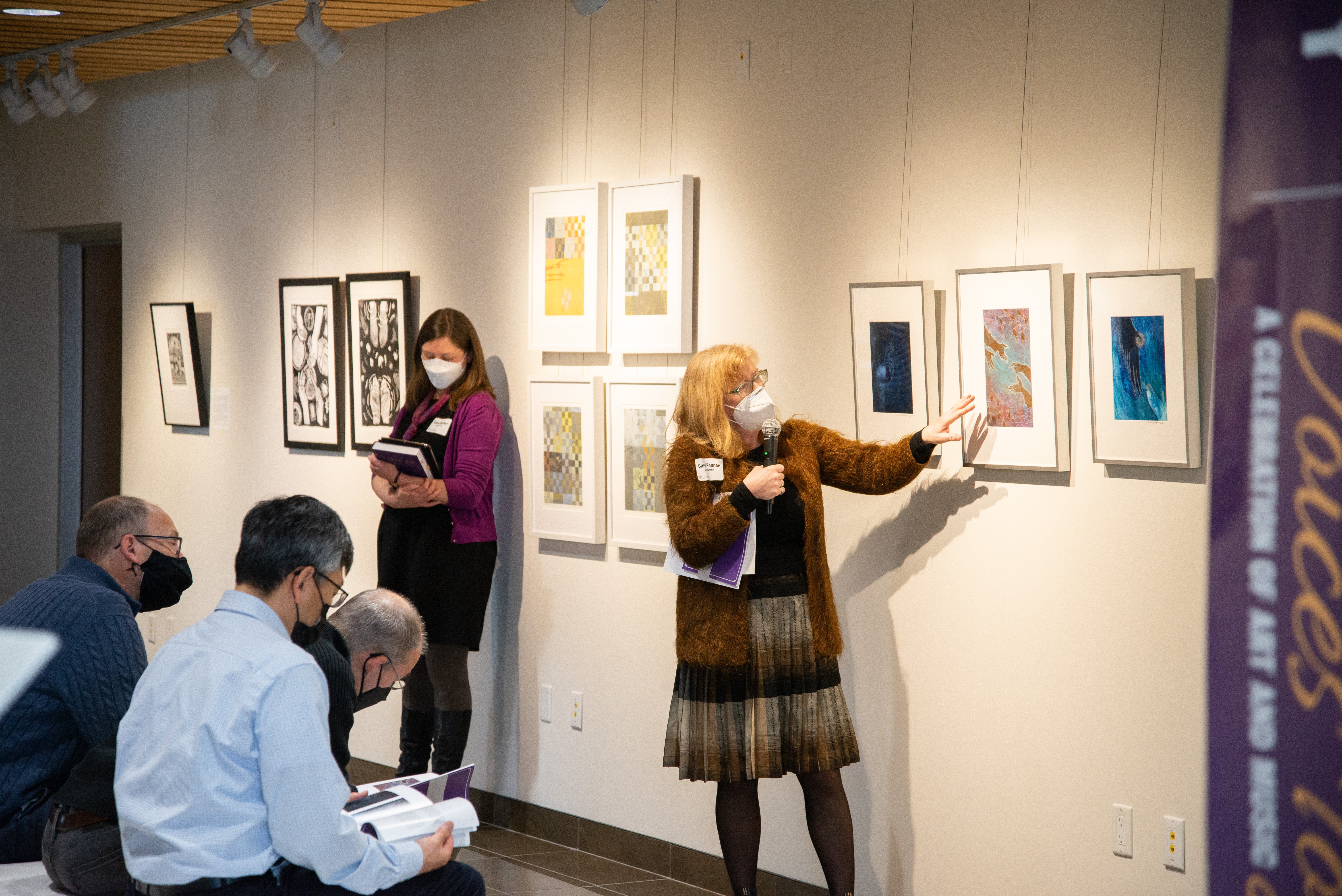 Carol Penner pointing at painting in Grebel Gallery