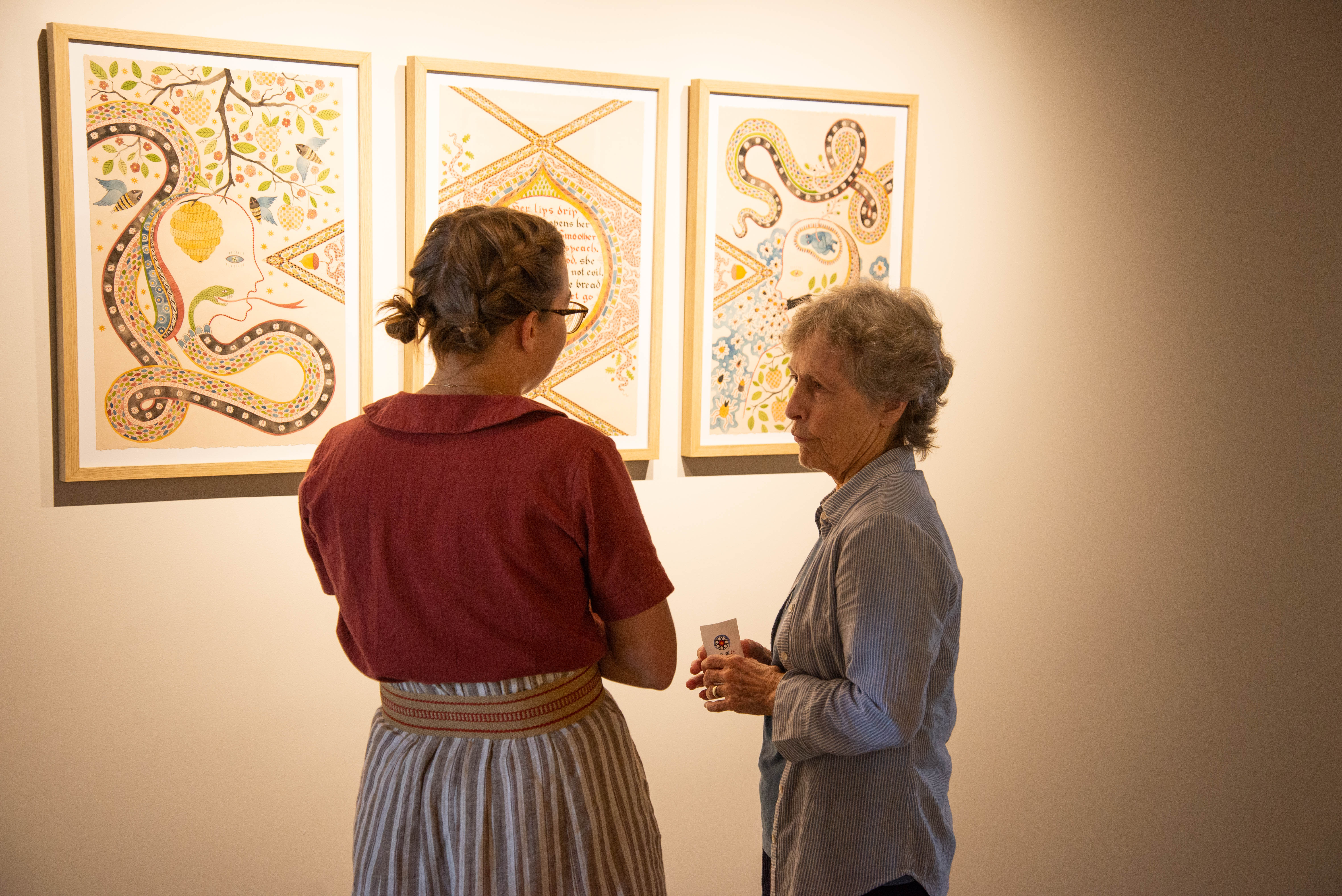 Two people standing in front of painting in Grebel Gallery talking