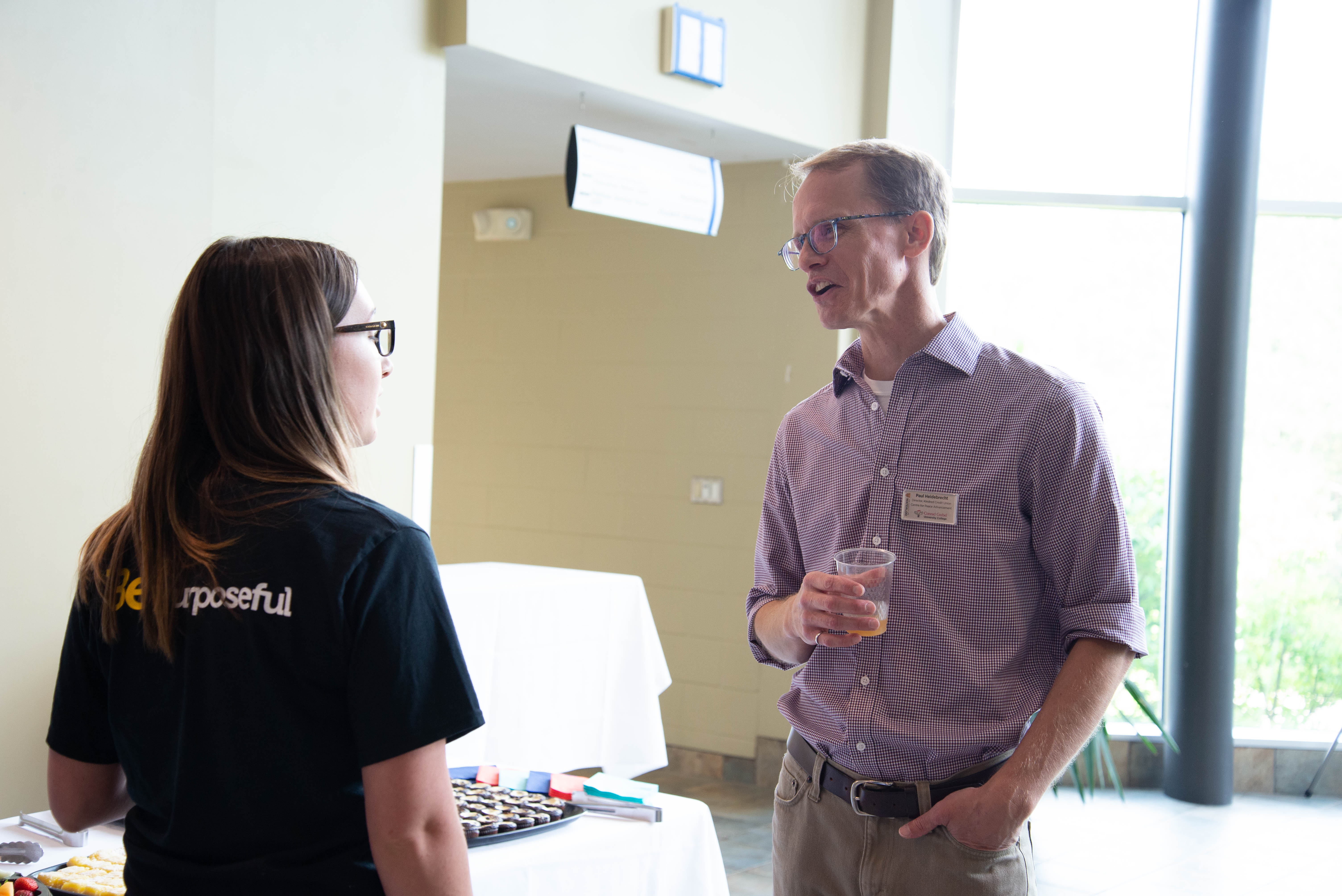 Paul Heidebrecht talking with a student beside appetizer table