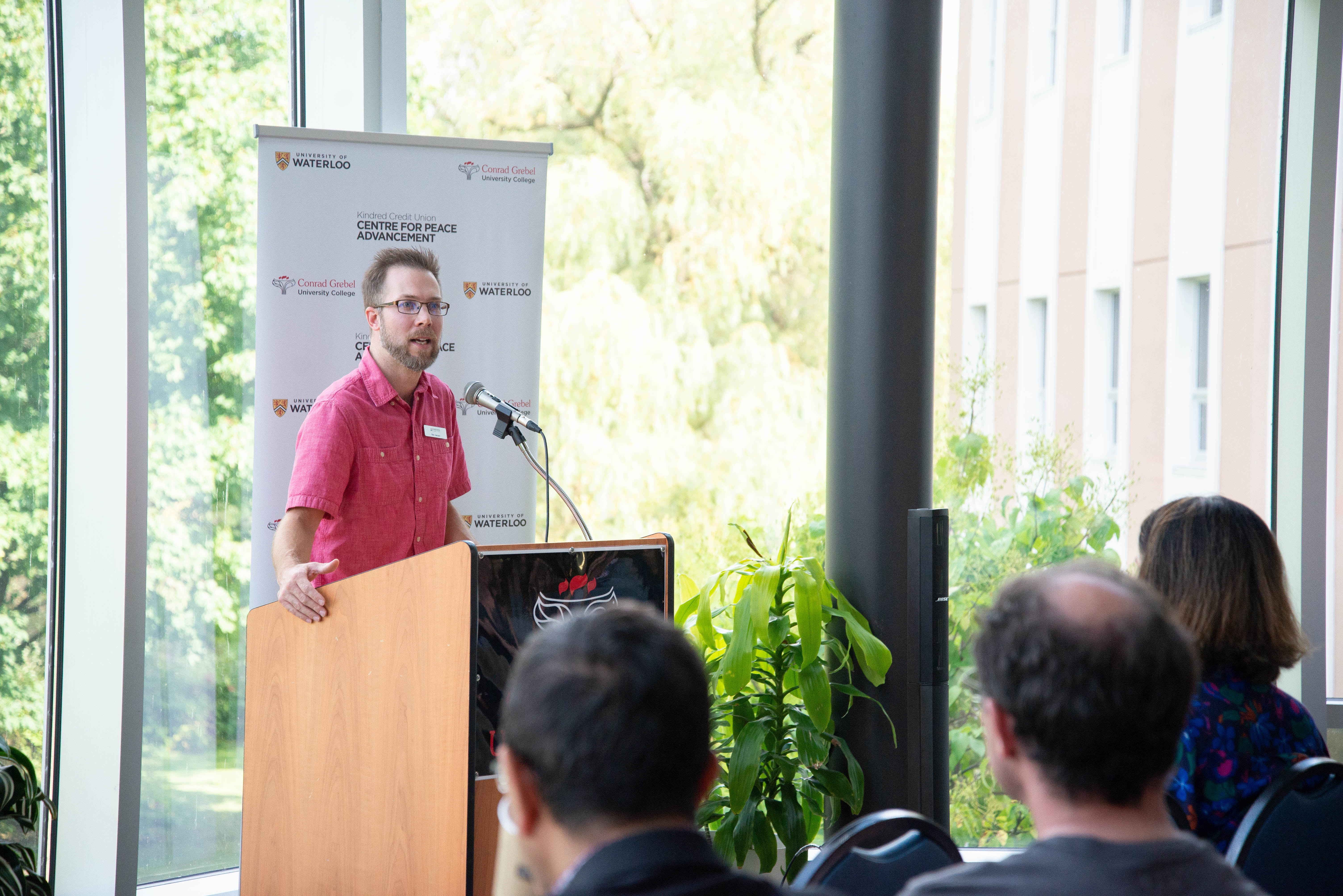 Nolan Andres speaking to crowd in Grebel Atrium