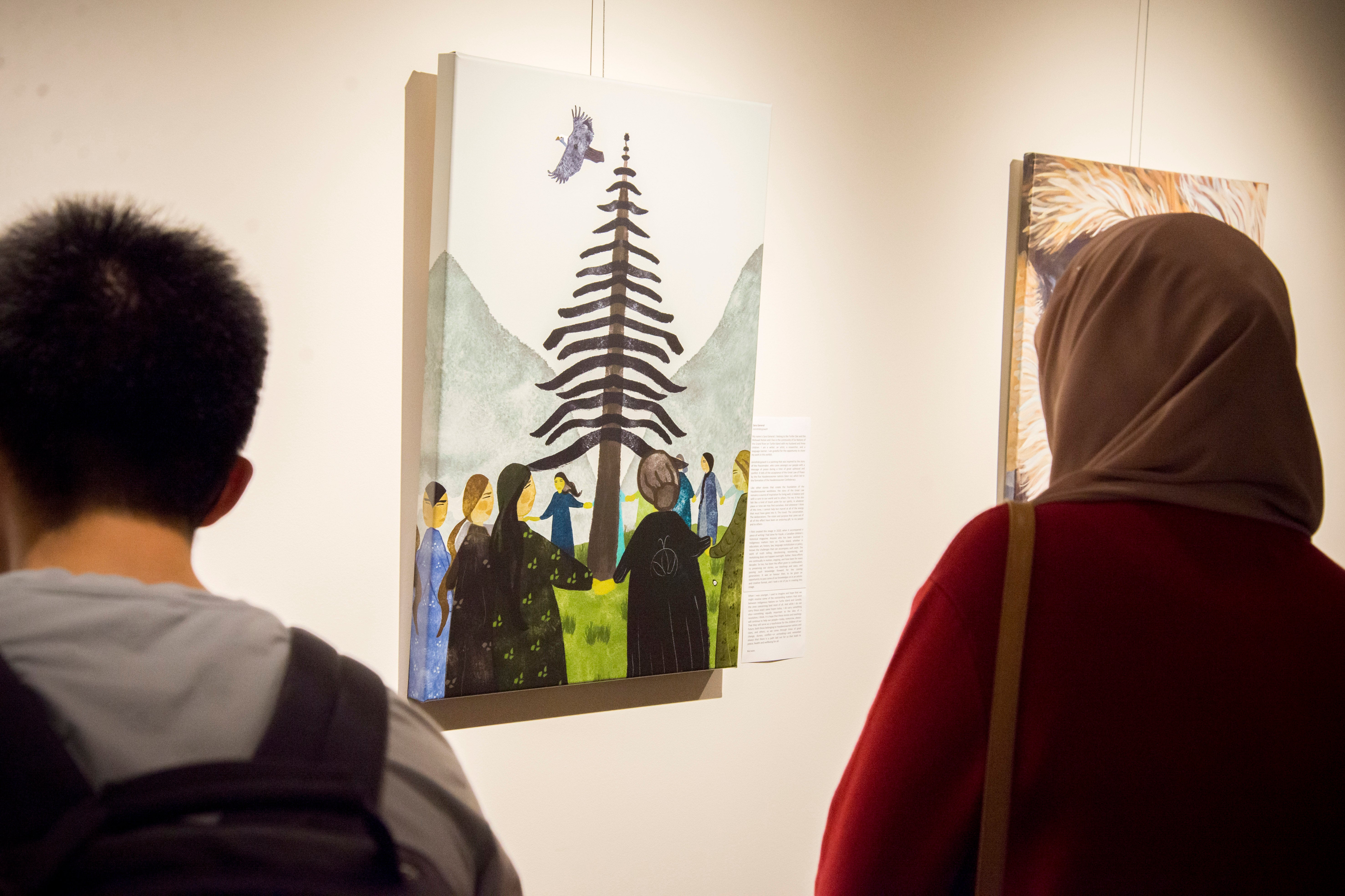 Two people looking at a picture of a tree in the Grebel Gallery