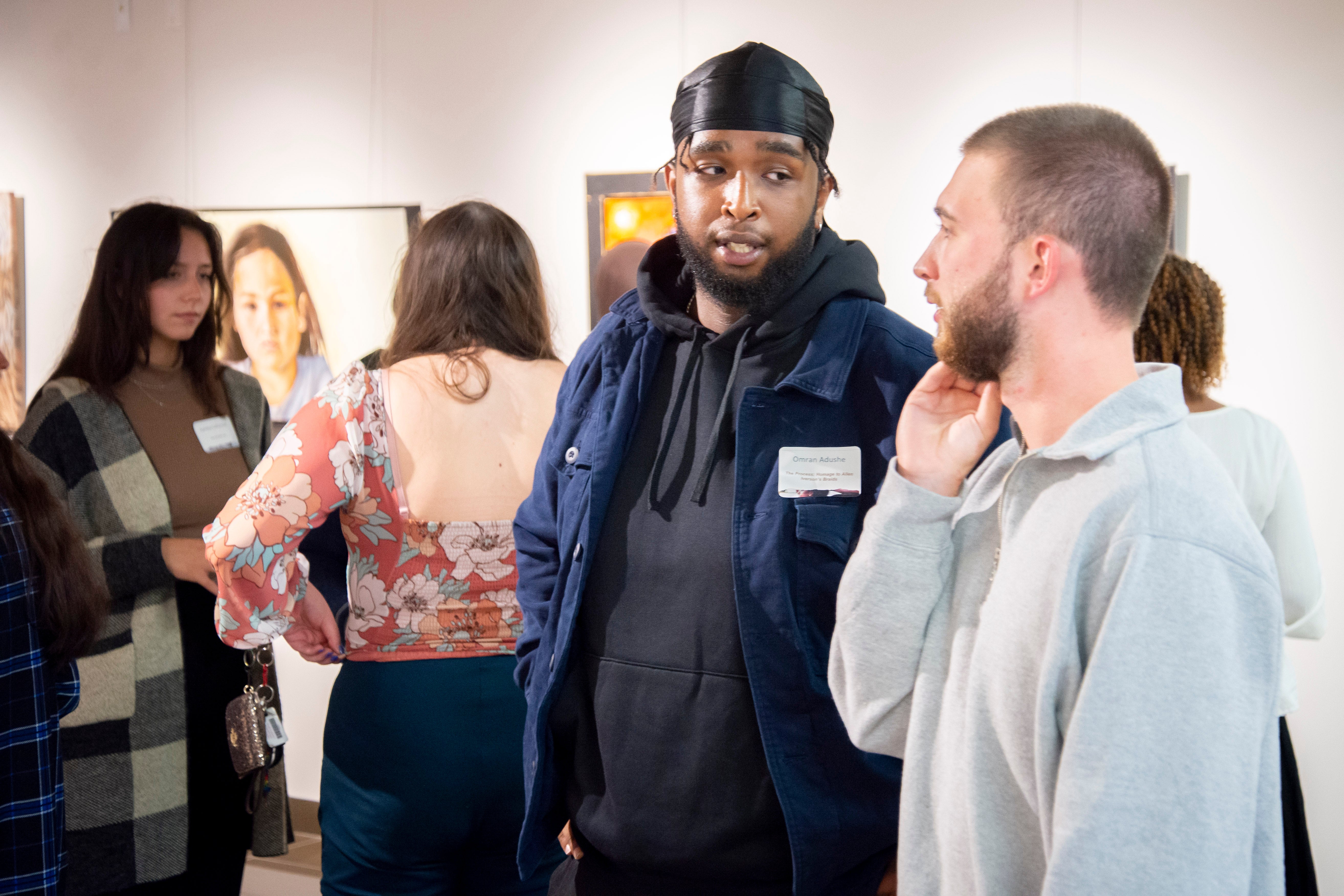 Two visitors to the Grebel Gallery chatting in a large group