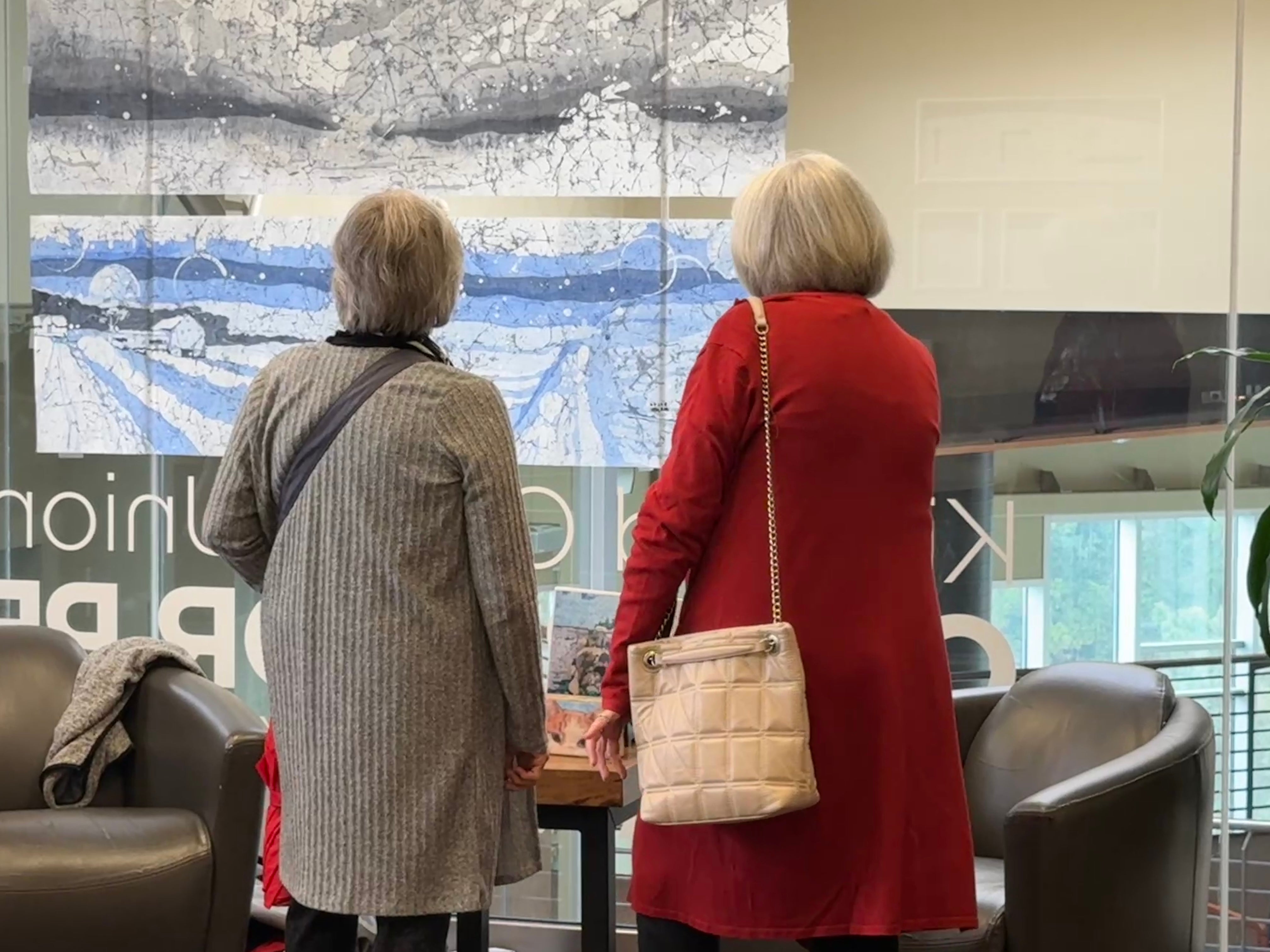 Two women looking at the wide skyline pictures on the internal glass wall