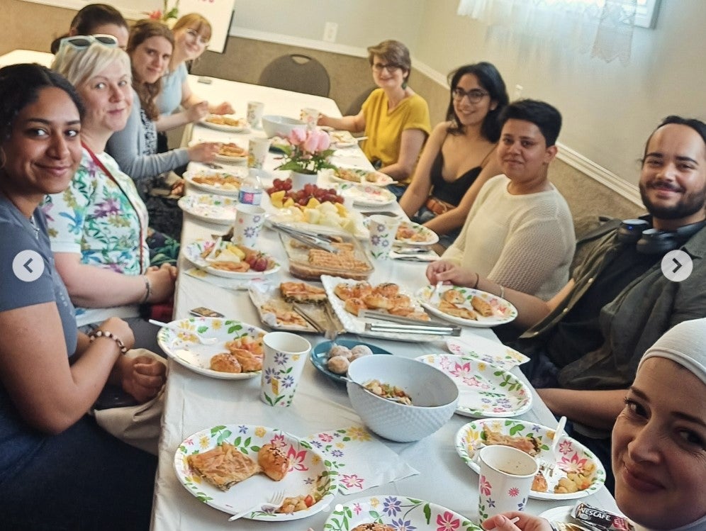 A diversity of people sharing an iftar meal around a table