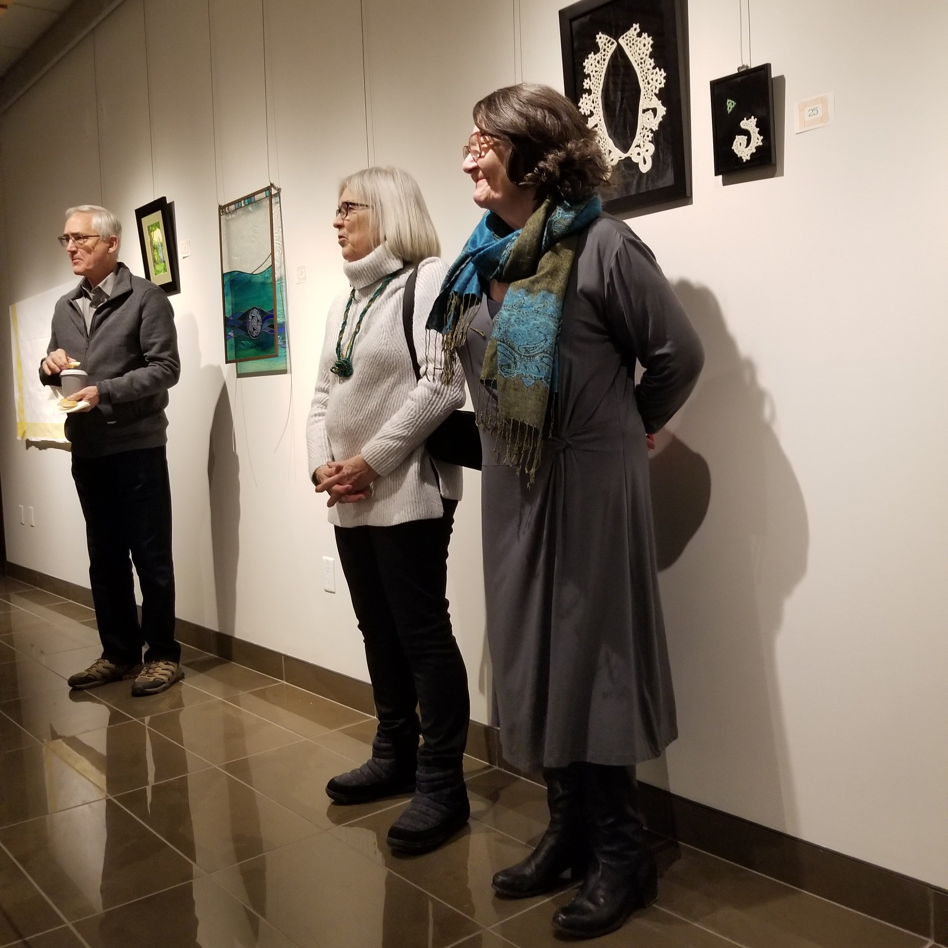 two women and a man lined up against a wall of art 