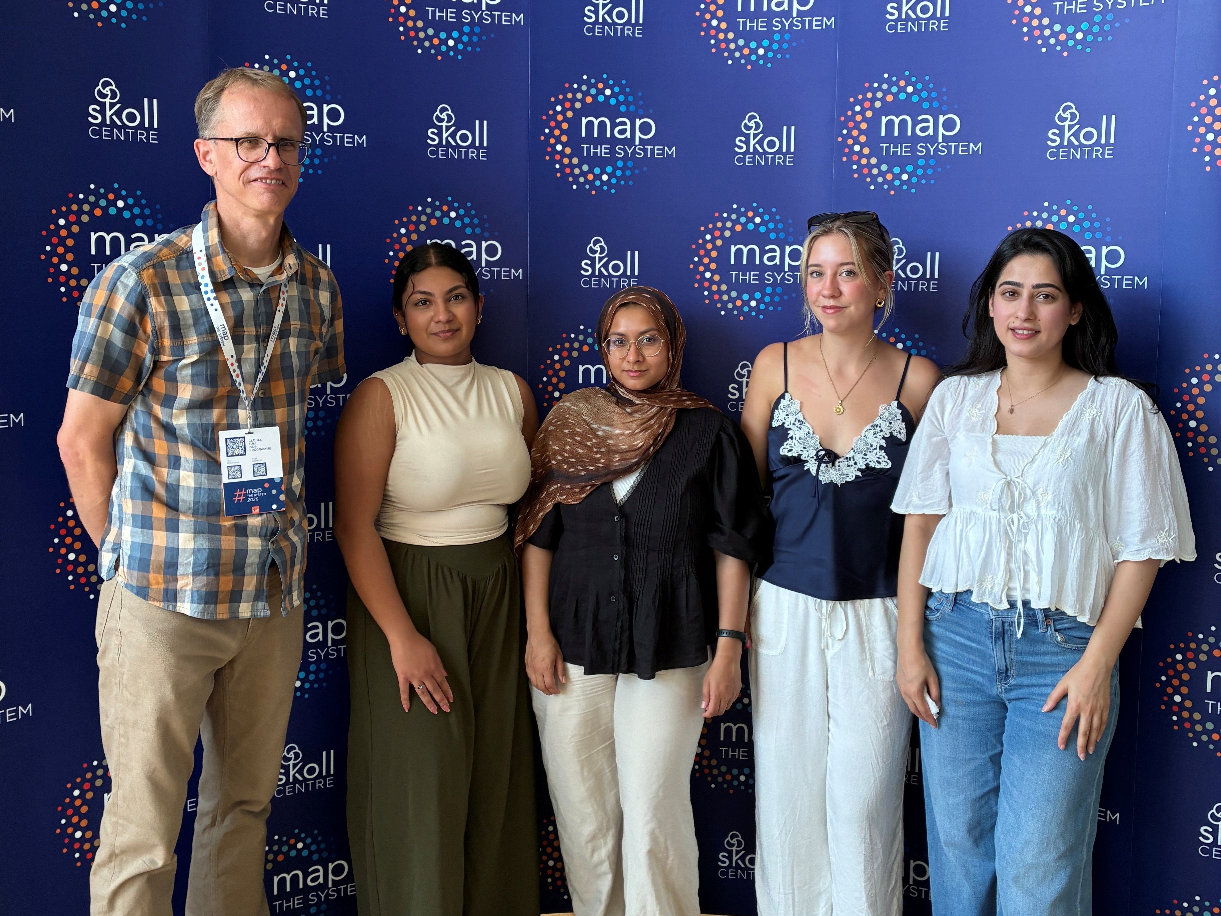 Paul, Prishaa, Sadia, Chloe and Zaraiz pose in front of a Map the System backdrop