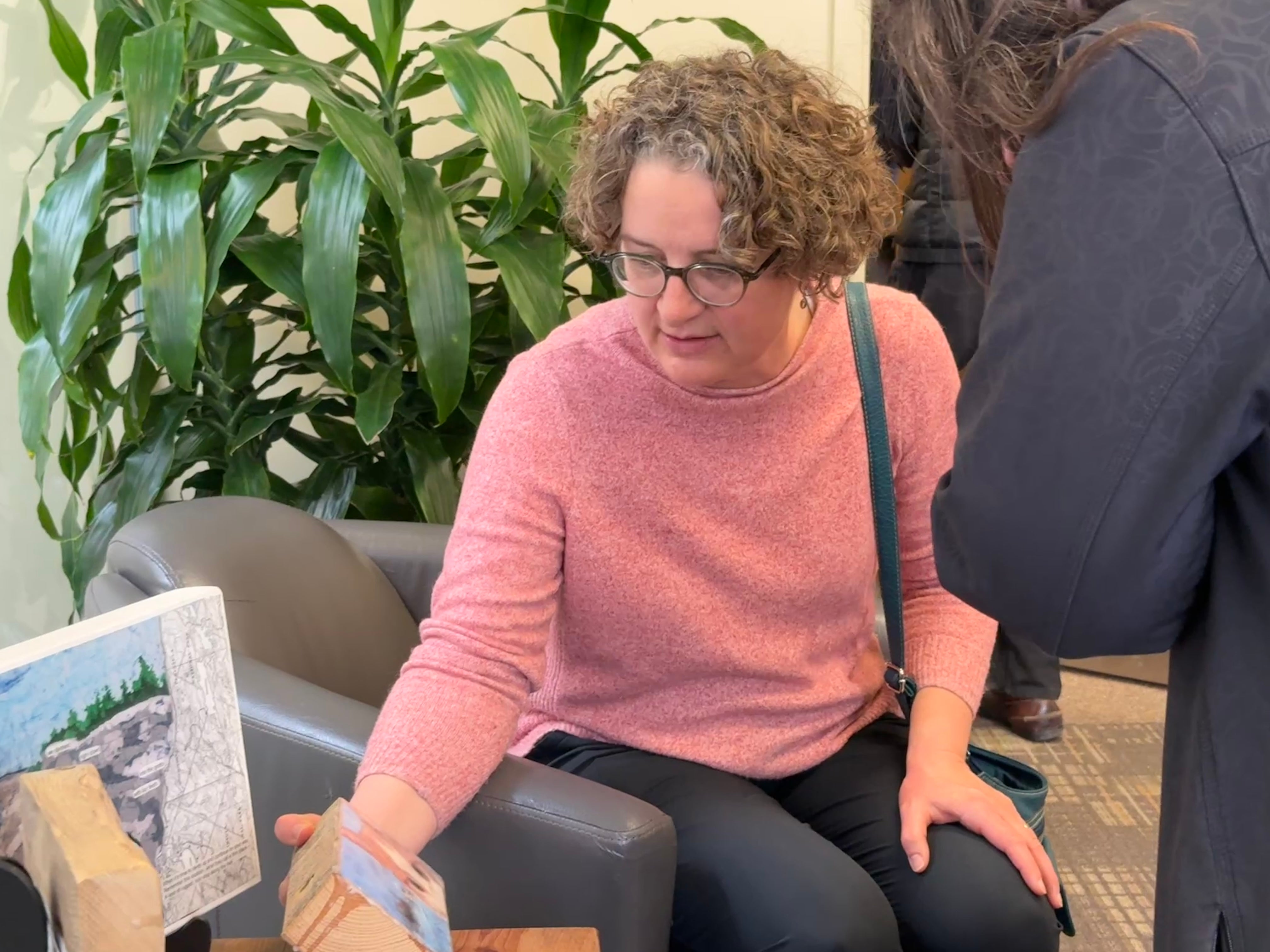 Woman feeling the weight of the art on wood that viewers were invited to touch