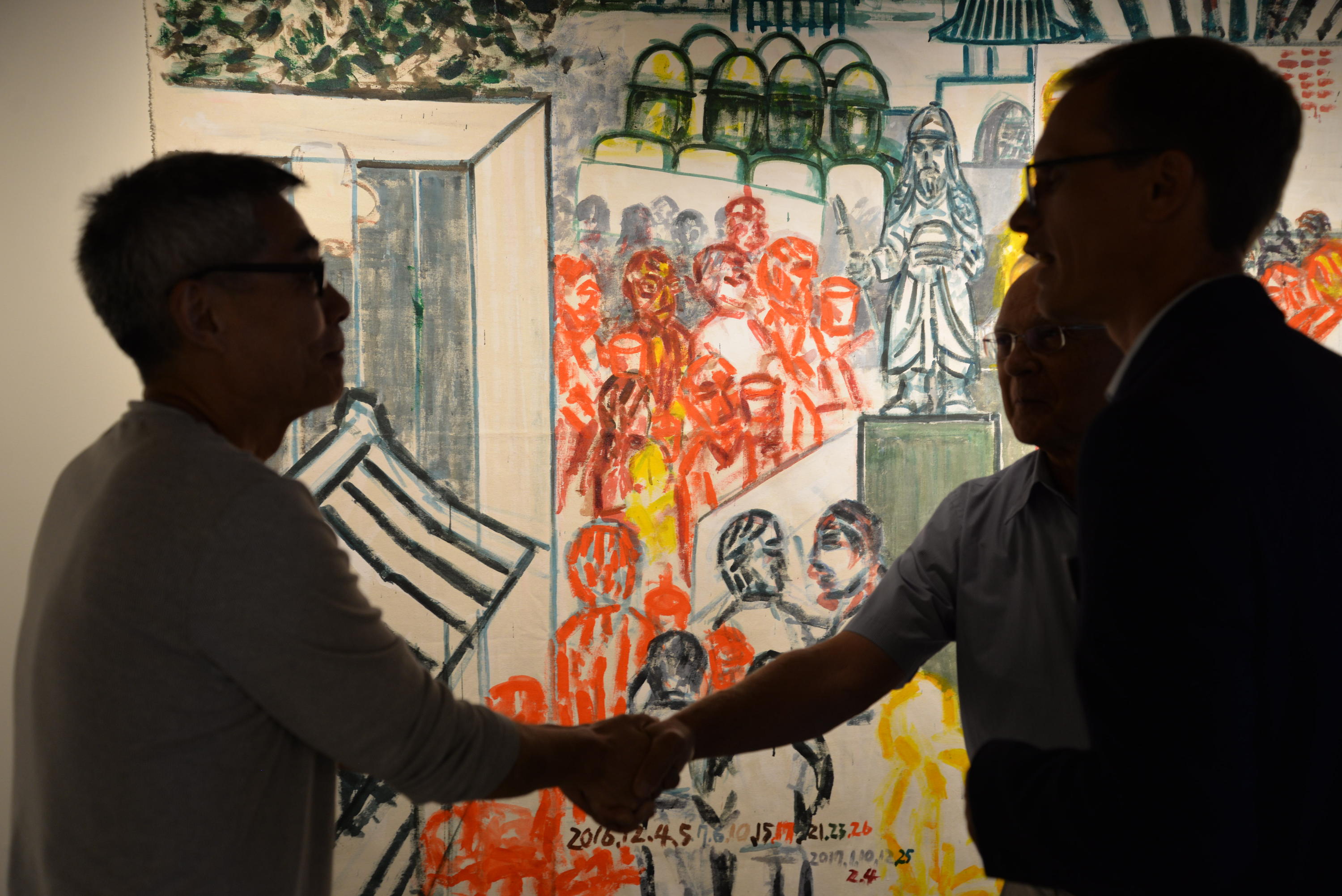 Two men shaking hands with art in background 
