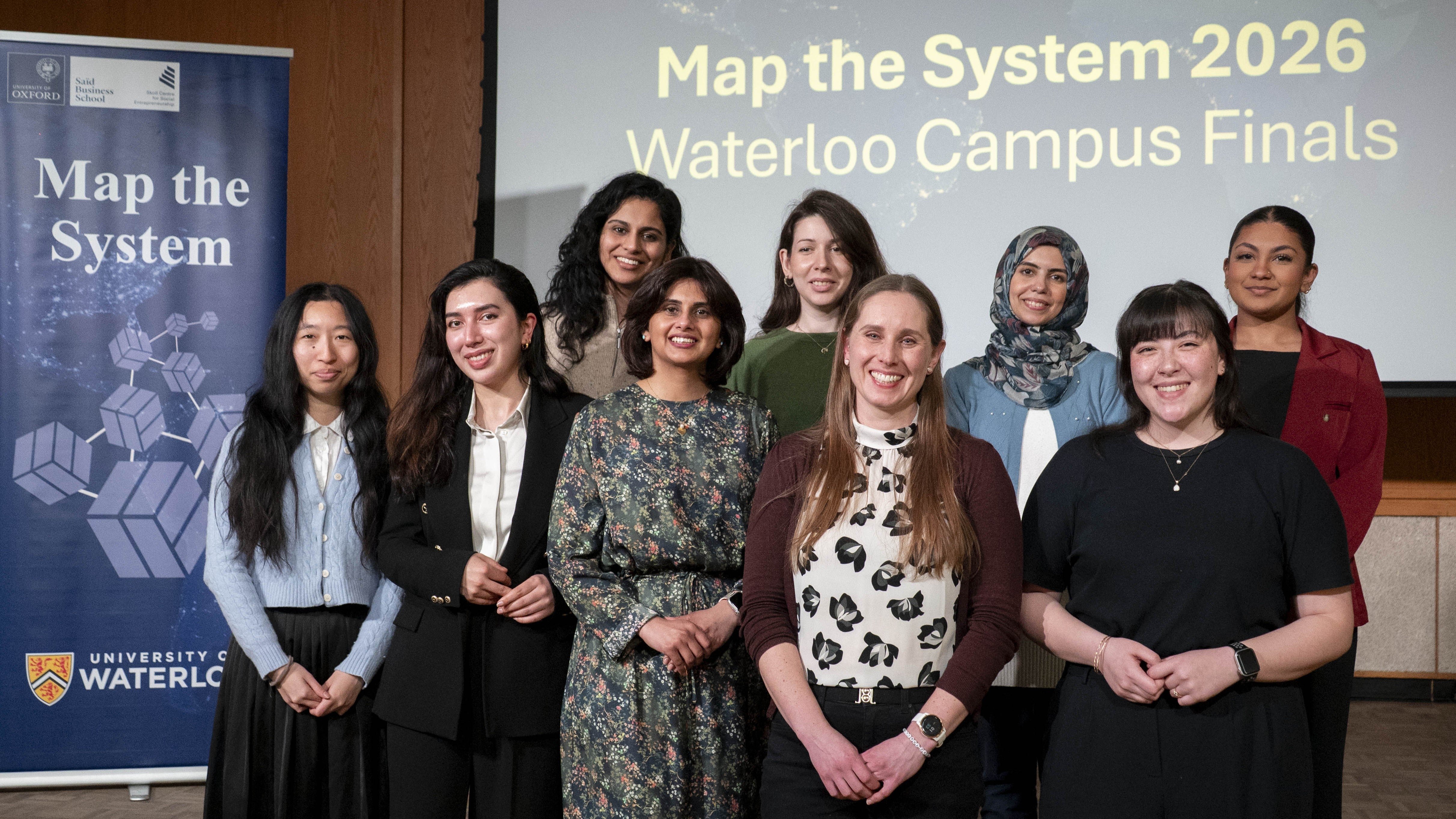 All finalists stand in front of the Map the System banner at the 2026 campus finals