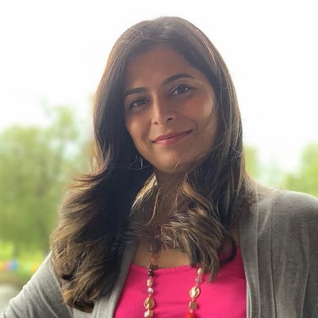 Rashmi smiling in front of a summery tree