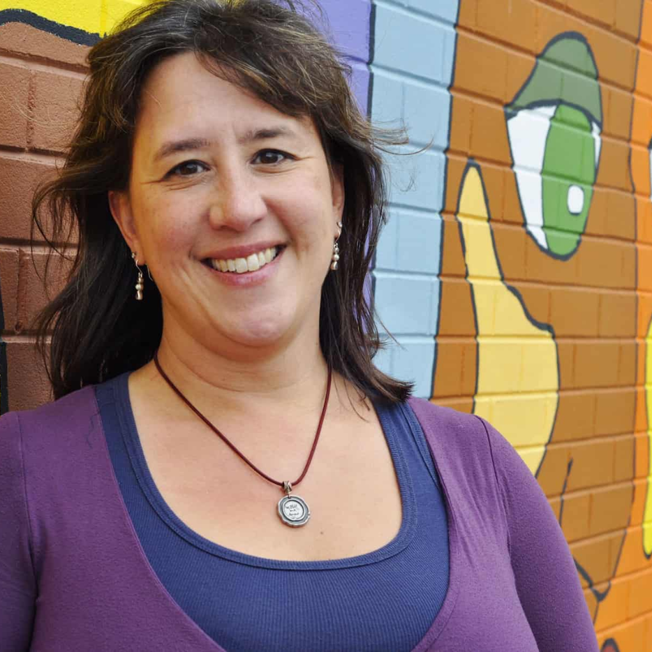 woman smiling in front of mural