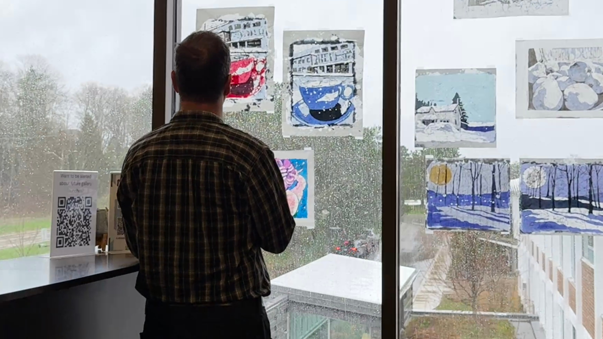 man looking at art on windows