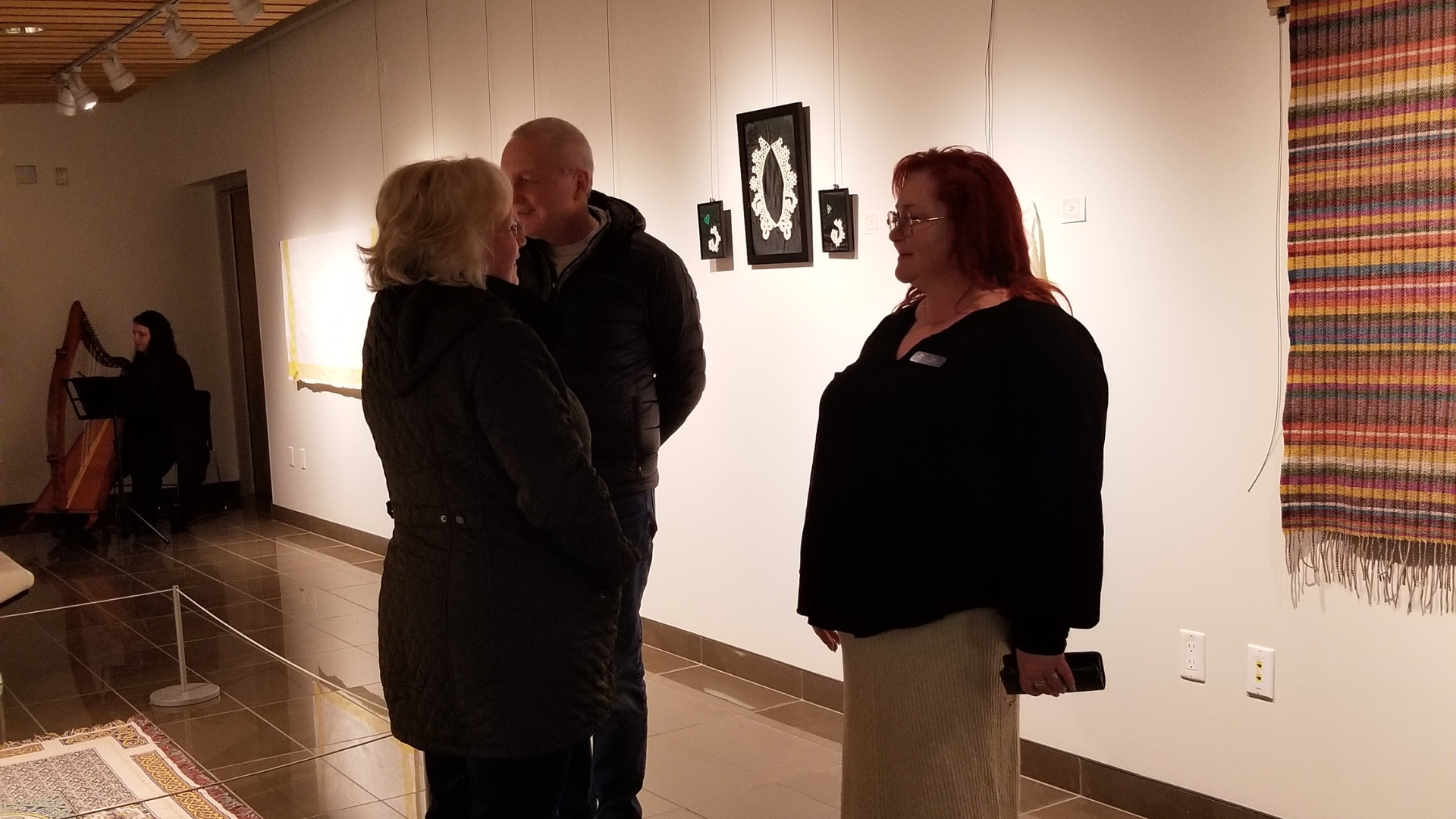 three people talking in front of art pieces on a wall