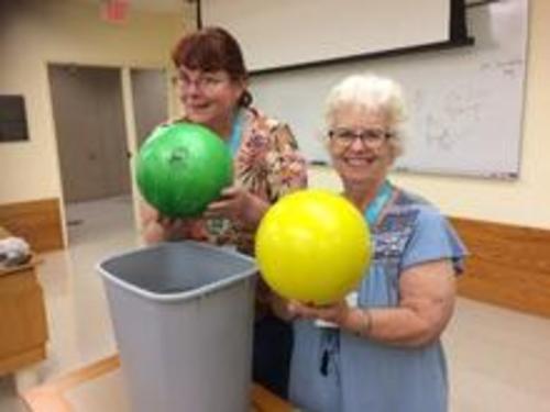 ChemEd Reg Friesen Lecturer Diana Mason and Robyn Ford holding bowling balls near a large bucket of water