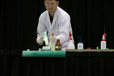 Man giving chemistry demonstration with green flame.