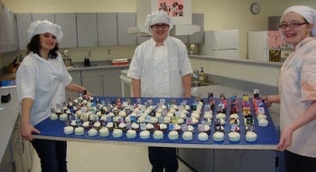 Students holding cupcakes that combine into a Periodic Table.