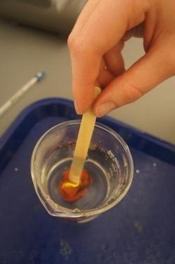 Hand stirring thermoplastic polymer with popsicle stick.